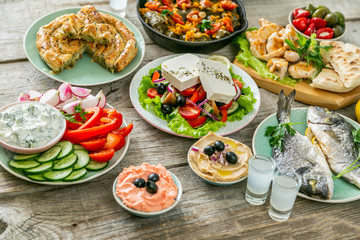 Selection of traditional greek food - salad, meze, pie, fish, tzatziki, dolma on wood background,