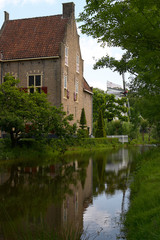 Fototapeta na wymiar Old traditional Dutch house and mill along a river with reflection in the Netherlands