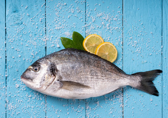 Seabream with vegetables on blue wooden background