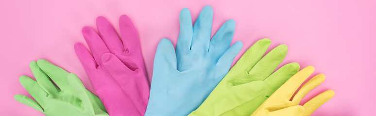 panoramic shot of multicolored rubber gloves on pink background