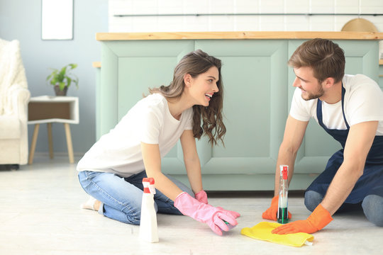 Young happy couple is having fun while doing cleaning at home.