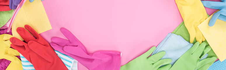 panoramic shot of multicolored rags and rubber gloves on pink background with copy space