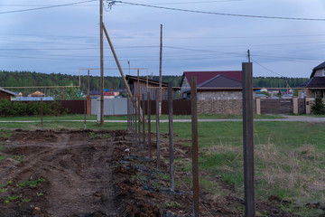 Fototapeta na wymiar fence construction, concreted metall column. Evening, sunset