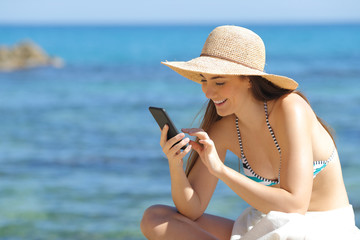 Happy sunbather using smart phone on the beach