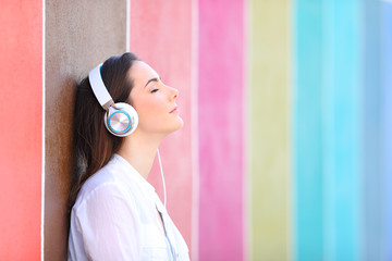 Relaxed girl listens to music in a colorful street