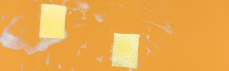 panoramic shot of of yellow sponges with foam on orange background