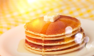 Stack of Small pancakes in syrup on background