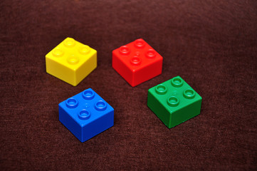 Four small building blocks of different colors on a brown background