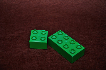 Two different size green building blocks on a brown background