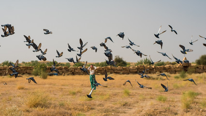 flock of doves flying in front of a girl