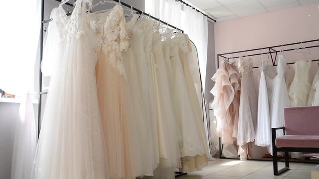 Many wedding dresses on the hangers in modern interior salon. Wedding shop interior