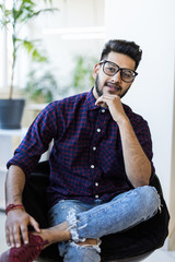 Young indian man in casual wear sitting in chair in his modern office