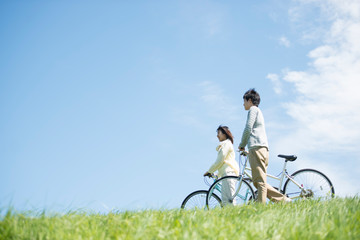 Obraz premium 草原で自転車を押すカップル