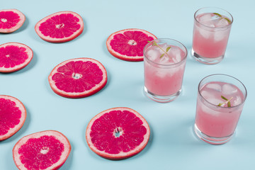 Fresh slices of ripe grapefruit and cold juice on blue background