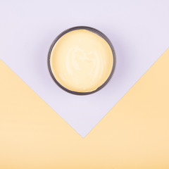 An elevated view of yellow paint container on dual paper background