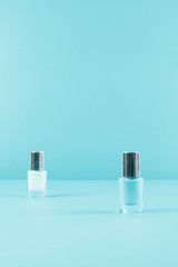 Two nail polish bottles on blue background with copy space for writing the text