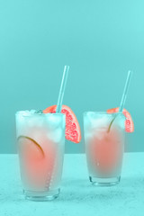 Two glasses of refreshment grapefruit cocktail on mint background
