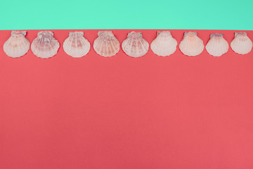 Mint stripes with row of scallop seashells against coral background with copy space for writing the text
