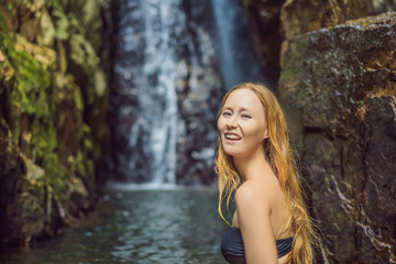 Young beautiful woman standing in the water at the waterfall