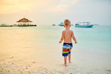 Three year old toddler boy on beach at sunset