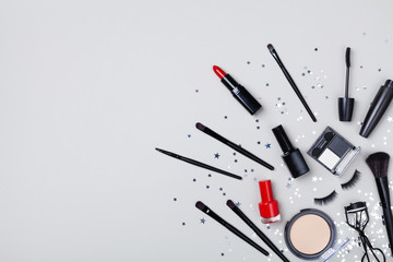Set of decorative cosmetic and beauty products for makeup on star confetti background top view....