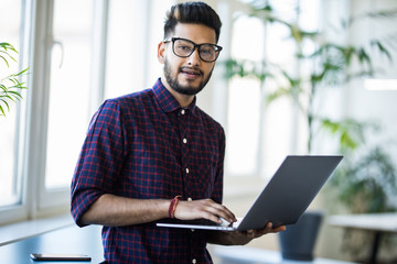 Portrait of Indian man frustrated with work sitting in front of a laptop.