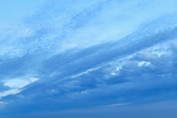 Blue clouds on a blue slightly twilight sky, divide the frame diagonally. Lower right corner with dense clouds. And the upper left with more transparent and rare.