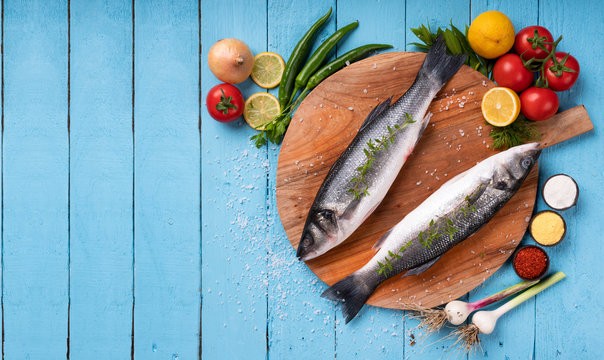 Sea bass fish with vegetables on blue board ground
