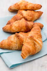Tasty buttery croissants on old wooden table.