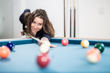 Fashionable modern woman playing pool table snooker game.