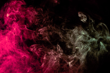 Beautiful column of smoke in the neon bright light of red, green, pink and turquoise on a black background exhaled out of the vape. Nice pattern for printing and backdrop of colored waves.