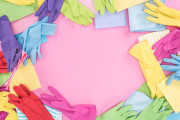top view of messy scattered multicolored rags and rubber gloves on pink background with copy space
