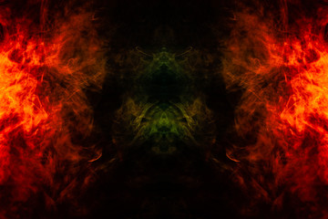 Fototapeta na wymiar Smoke of different orange and red colors in the form of horror in the shape of the fire on a black isolated background. Soul and ghost in mystical symbol