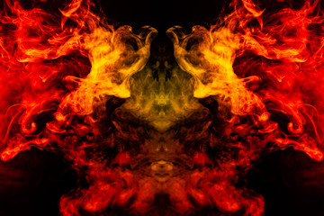 Smoke of different orange and red colors in the form of horror in the shape of the head, face and eye with wings on a black isolated background. Soul and ghost in mystical symbol