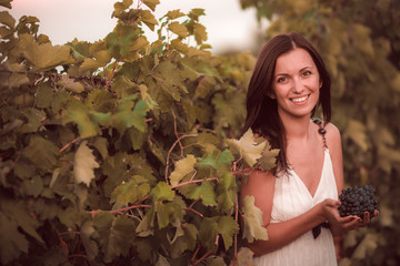 Smiling woman in white dress standing in vineyard