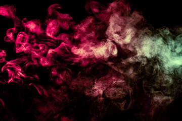 Beautiful column of smoke in the neon bright light of red, green, pink and turquoise on a black background exhaled out of the vape. Nice pattern for printing and backdrop of colored waves.