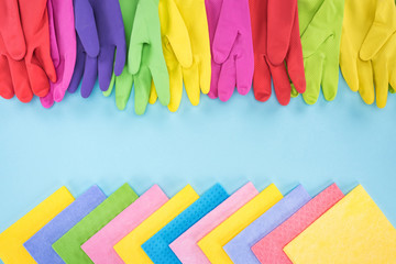 top view of multicolored bright rubber gloves and rags on blue background with copy space
