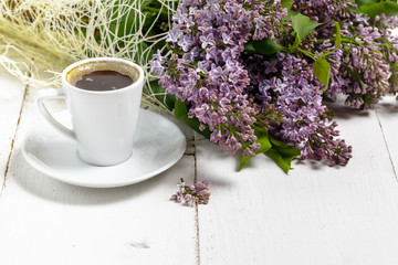 Coffee cup and colorful lilac flowers on garden table