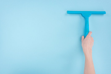 cropped view of woman holding squeegee on blue background