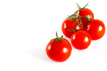 Red juicy cherry tomatoes with green tails lying on a white background