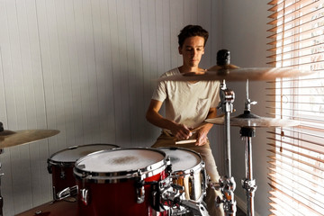 Enthusiastic drummer playing rock beat on practice drum kit.