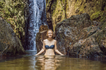Young beautiful woman standing in the water at the waterfall