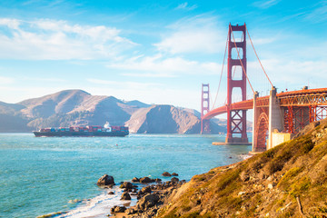 Golden Gate Bridge with cargo ship at sunset, San Francisco, California, USA
