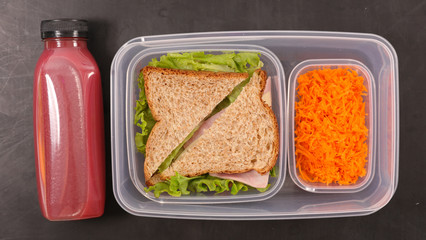 lunch box with sandwich, carrot and fruit juice