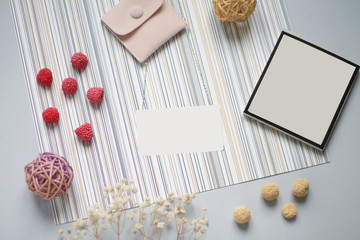 on a blue background sprig flower black blueberries and red white marshmallows grey envelope pink writing tablet and business card