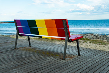 Rainbow LGBT pride flag painted on a wooden bench.