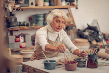 Serious aged woman working in the workshop