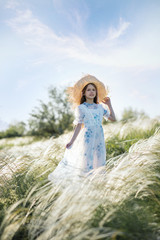 Fototapeta premium Girl in a straw hat in the fields. The girl with long hair walks on the field in the summer. Baby smile