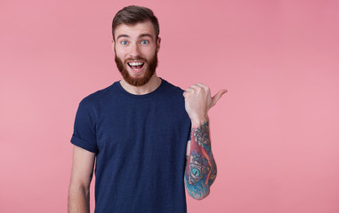 Prttrait of young happy red-bearded young guy ,with wide open mouth in surprise, wearing a blue...