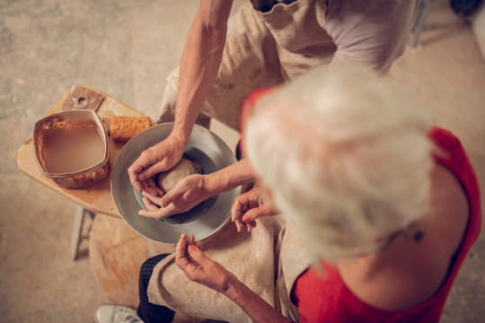 Top view of male hands holding a ball from clay